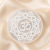 Selenite OM Charging Plate displayed fully on white silk cloth to show its natural colour, shape and finish