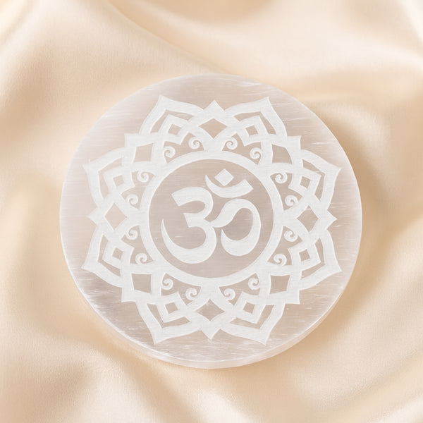 Selenite OM Charging Plate displayed fully on white silk cloth to show its natural colour, shape and finish