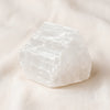 Selenite Raw Stone displayed fully on white silk cloth to show its natural colour, shape and finish