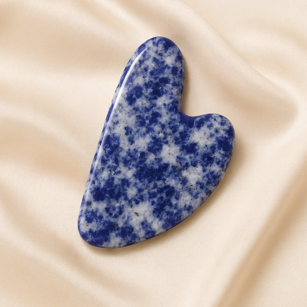 Sodalite Gua Sha displayed fully on white silk cloth to show its natural colour, shape and finish
