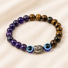 Tiger Eye, Amethyst & Evil Eye Bracelet displayed fully on white silk cloth to show its natural colour, shape and finish