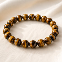 Load image into Gallery viewer, Tiger Eye Bracelet displayed fully on white silk cloth to show its natural colour, shape and finish
