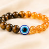 Tiger Eye, Citrine & Evil Eye Bracelet displayed fully on white silk cloth to show its natural colour, shape and finish