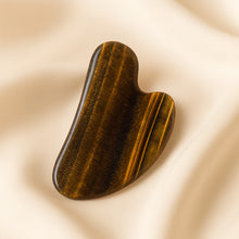 Load image into Gallery viewer, Tiger Eye Gua Sha displayed fully on white silk cloth to show its natural colour, shape and finish
