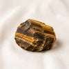 Tiger Eye Raw Stone displayed fully on white silk cloth to show its natural colour, shape and finish