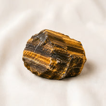 Load image into Gallery viewer, Tiger Eye Raw Stone displayed fully on white silk cloth to show its natural colour, shape and finish
