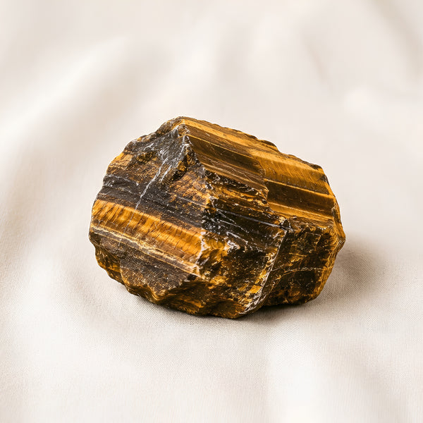 Tiger Eye Raw Stone displayed fully on white silk cloth to show its natural colour, shape and finish