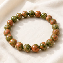 Load image into Gallery viewer, Unakite Bracelet displayed fully on white silk cloth to show its natural colour, shape and finish
