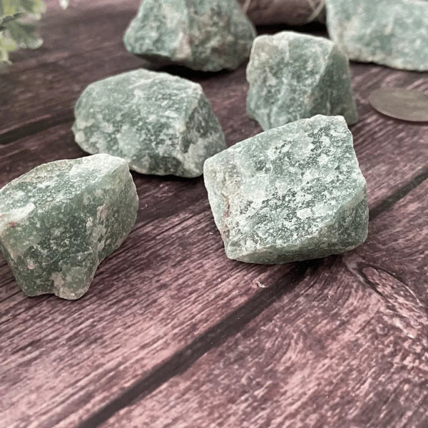 Green Aventurine raw stones arranged on a wooden table symbolizing luck, opportunity, and growth.