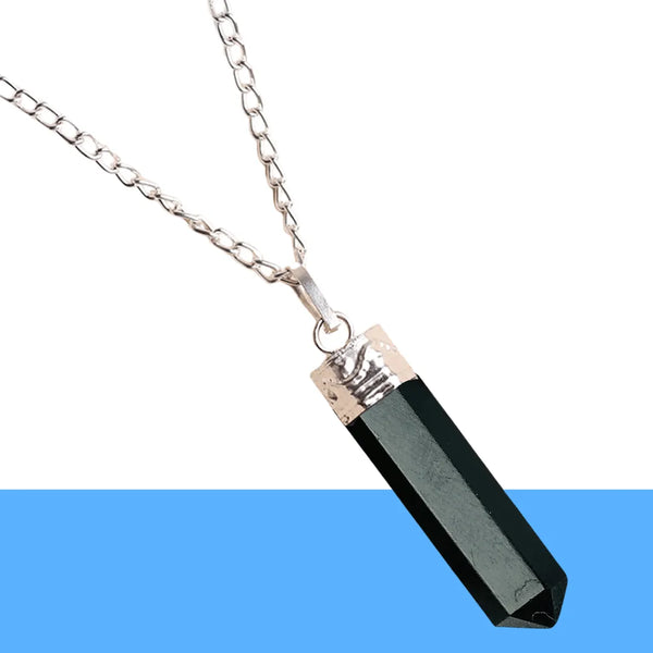 Hexagonal black obsidian pendant with silver detailing placed on a bright white surface.
