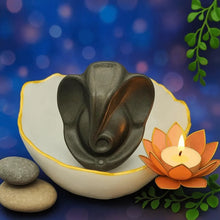 Load image into Gallery viewer, Lord Ganesha decorative showpiece placed in a white bowl with a lotus candle and smooth stones for spiritual home décor.
