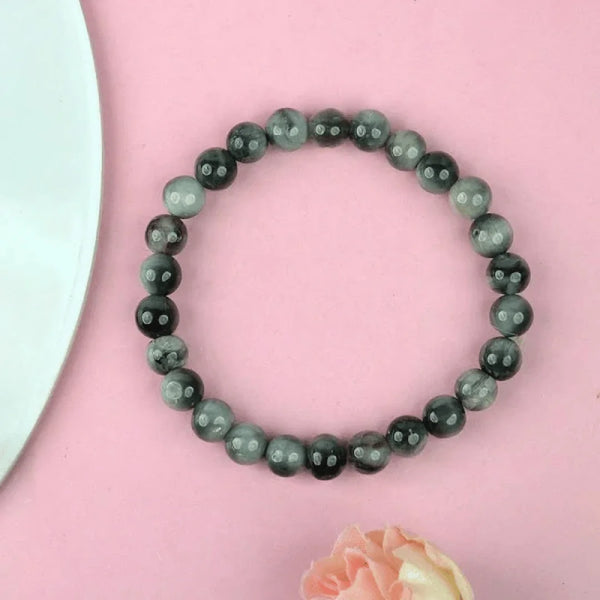 Natural grey bead bracelet resting on a pink tabletop