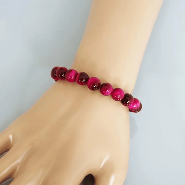 Close-up shot of a glossy red stone bracelet on a person’s wrist 