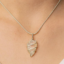 Load image into Gallery viewer, Opalite arrowhead crystal necklace on a pink background for jewelry display
