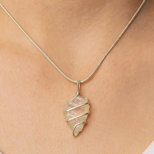 Opalite arrowhead crystal necklace on a pink background for jewelry display