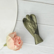 Load image into Gallery viewer, Pyrite angel figurine placed on a white wooden surface beside a soft pink rose
