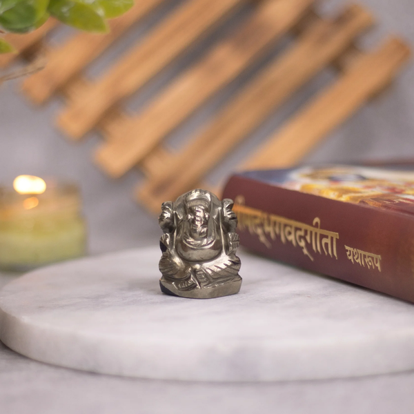 Pyrite Ganesh figurine with Geeta beside it, symbolizing abundance, prosperity and protection.