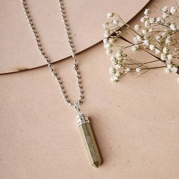 Pyrite point pendant with silver cap and chain displayed on a soft pink background.