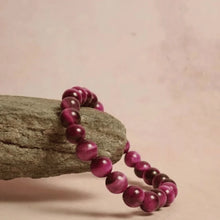 Load image into Gallery viewer, Red crystal bracelet displayed on a rugged rock.
