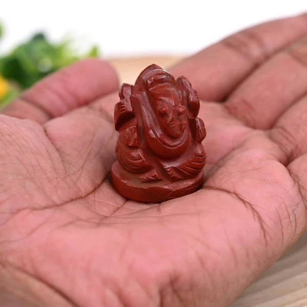 Red Jasper Ganesh crystal figurine held in hand, symbolizing protection, strength and success with natural healing energy.
