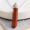 Close-up of a Red Jasper pencil pendant with a silver cap displayed against a white round stand and textured surface.