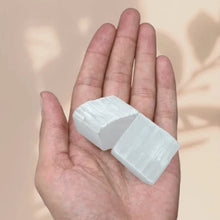 Load image into Gallery viewer, Selenite raw crystal cluster resting on the palm against a soft pink background, symbolizing cleansing and clarity.
