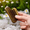 Tiger Eye Gua Sha face crystal held in hand, used for energizing massage, willpower and facial balance.