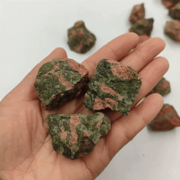 Unakite raw stones resting on the palm, symbolizing balance, healing, and personal growth.