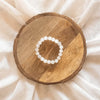 White bead bracelet placed on a round wooden table.